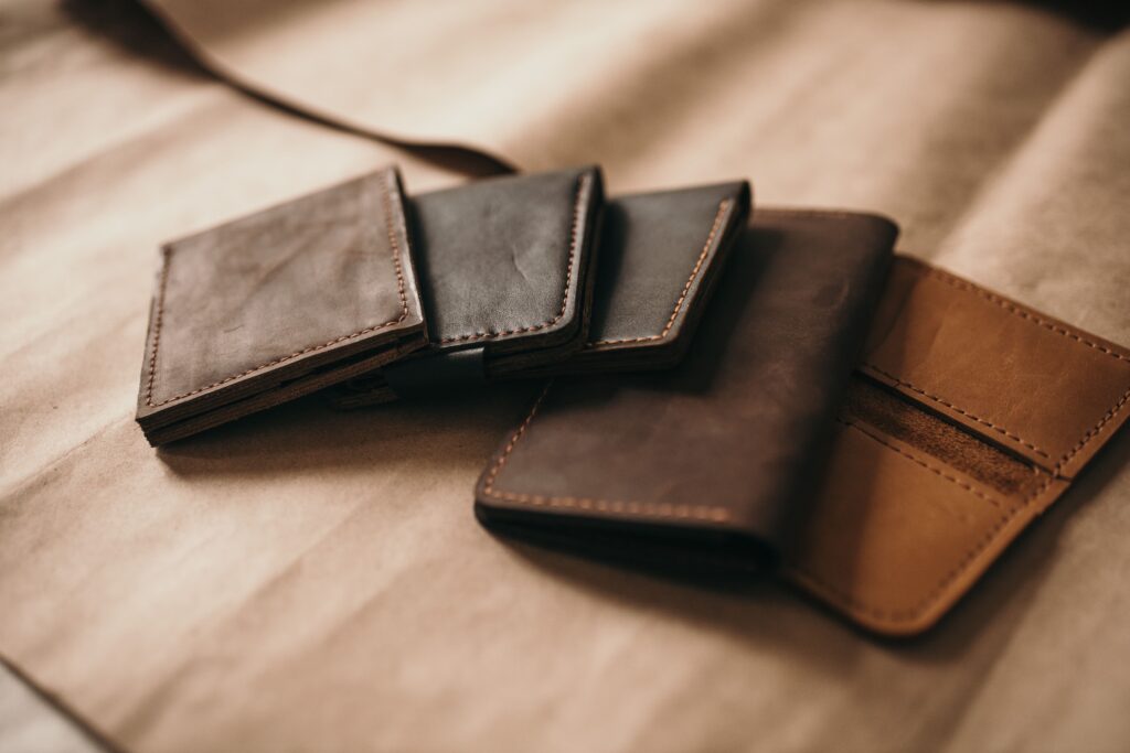 Porte-cartes en cuir marron et noir, disposés sur un fond beige.